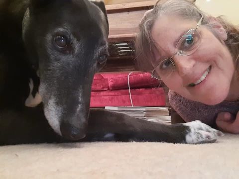Sarah and a lurcher laying on the carpet.